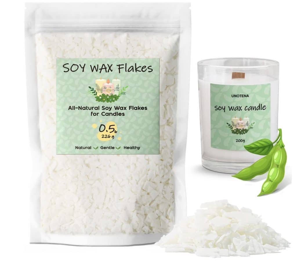 A package labeled "Soy Wax Flakes" features all-natural soy wax flakes for candle making. Beside it, a clear glass soy wax candle adorned with dried flowers rests next to a few soybeans. The flakes are displayed prominently, and the package touts the product as natural, gentle, and healthy.